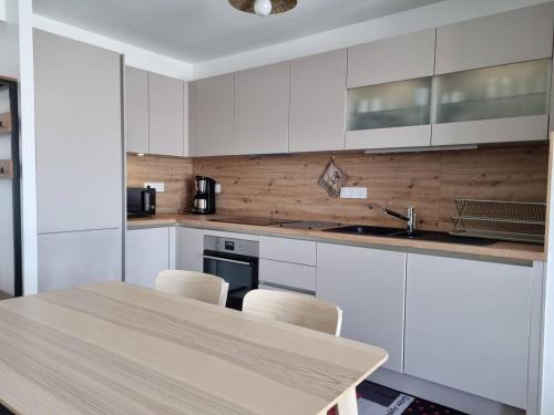 une cuisine avec des armoires blanches et une table et des chaises dans l'établissement Appartement neuf climatisé, loggia spacieuse, à 200m de la mer avec parking privé - FR-1-388-206, à Argelès-sur-Mer