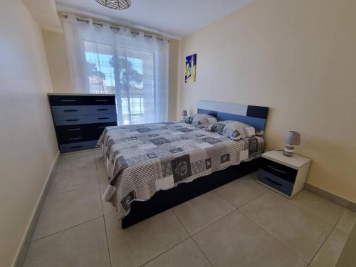 une chambre avec un lit, une commode et une fenêtre dans l'établissement Appartement neuf climatisé, loggia spacieuse, à 200m de la mer avec parking privé - FR-1-388-206, à Argelès-sur-Mer