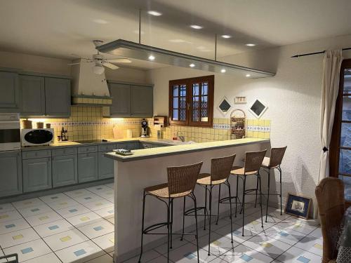 une cuisine avec un îlot et des tabourets de bar dans l'établissement Maison de plain pied avec terrasse, 2 chambres, proche plage et centre-ville, climatisée et PMR - FR-1-225C-102, à Banyuls-sur-Mer