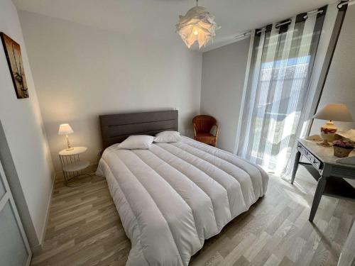 Schlafzimmer mit einem großen weißen Bett und einem Schreibtisch in der Unterkunft Appartement Étel, 2 pièces, 4 personnes - FR-1-479-126 in Étel