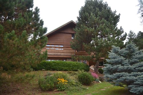 a wooden house with trees and flowers in front of it at Chata Dolce in Trutnov