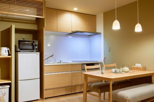 a kitchen with a table and a white refrigerator at Reikyo Garden Osaka in Osaka