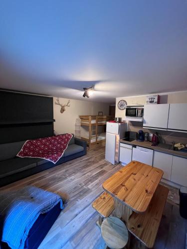 a room with a table and a kitchen with a bed at Studio L'Ecrin des Ecureuils in La Féclaz