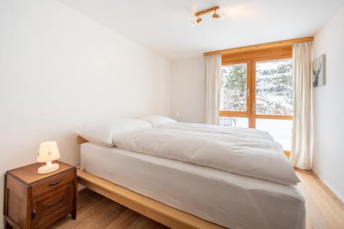a bedroom with a bed with a nightstand and a window at Casa Collina 5i-02 in Flims