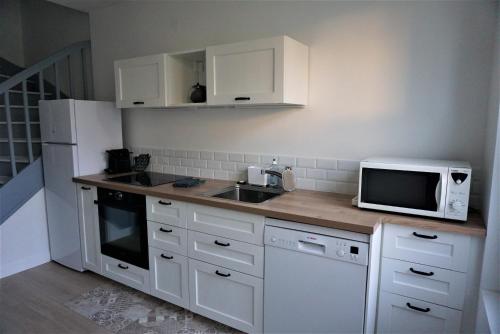 cocina con armarios blancos, fregadero y microondas en Les Beaux Jours, Tours, le Duplex, en Tours