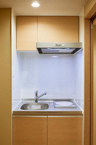 a kitchen with a sink and wooden cabinets at Reikyo Garden Osaka in Osaka