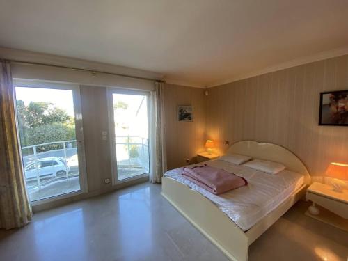 a bedroom with a bed and a sliding glass door at Quiberon - Grand 2 pièces avec balcon et parking, face à la plage - FR-1-478-4 in Quiberon
