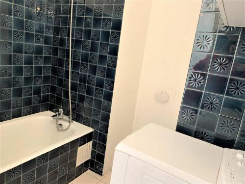 La salle de bains est pourvue d'un mur carrelé bleu et d'une baignoire. dans l'établissement Studio cosy à Quiberon avec parking et animaux admis, face à la mer - FR-1-478-87, à Quiberon