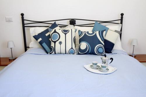 Una cama con almohadas azules y blancas y una bandeja de tazas de café. en Nonna Maria Guest House, en Arezzo