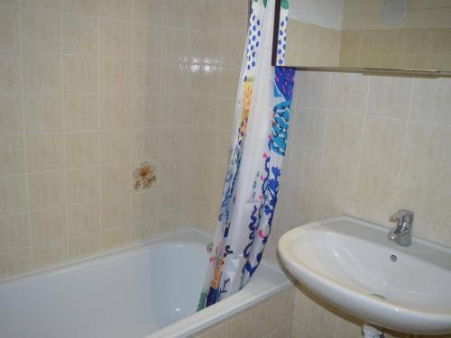 La salle de bains est pourvue d'un lavabo, d'une baignoire et d'un rideau de douche. dans l'établissement Banyuls : Studio cabine, terrasse, proche plage - FR-1-225C-30, à Banyuls-sur-Mer