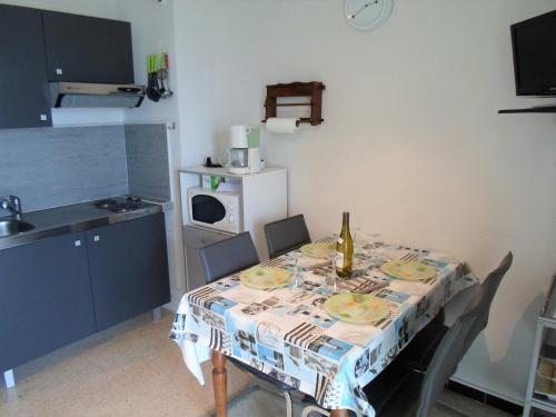 - une cuisine avec une table et une bouteille de vin dans l'établissement Appartement climatisé avec balcon, proche des Thermes et de l'Étang de Thau - FR-1-503-57, à Balaruc-les-Bains