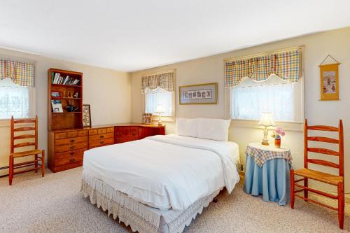 a bedroom with a white bed and two chairs at 262 Ghia Farm Road in Ludlow