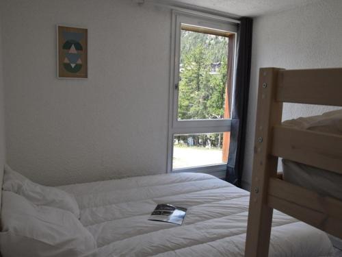 - une chambre avec un lit et une fenêtre avec un livre dans l'établissement Bel appartement 2 pièces avec WIFI, parking, au pied des pistes de ski à Montgenèvre - FR-1-266-145, à Montgenèvre