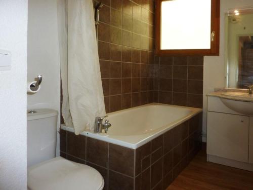 une salle de bain avec une baignoire, des toilettes et un lavabo dans l'établissement Grand appartement pour 8 avec piscine intérieure chauffée, jacuzzi et grande terrasse exposée sud - FR-1-322-378, aux Orres