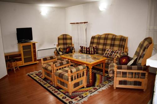 - un salon avec des canapés, une table et une télévision dans l'établissement Хотел-механа Павлова къща, à Chiprovtsi