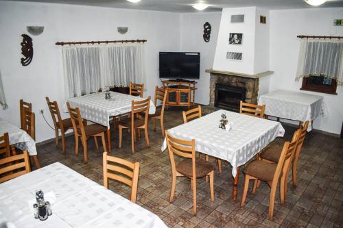comedor con mesas y sillas y TV en Хотел-механа Павлова къща, en Chiprovtsi
