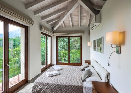 a bedroom with a large bed and large windows at Villa Elena in Menaggio
