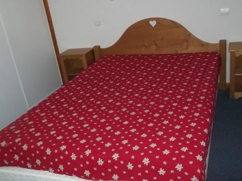 ein Bett mit einer roten Tagesdecke und weißen Blumen drauf in der Unterkunft Appartement Orcières Merlette, 3 pièces, 6 personnes - FR-1-262-167 in Orcières