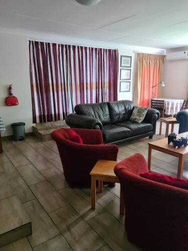 a living room with a black leather couch and chairs at Hornbill Helipad 1 in Centurion