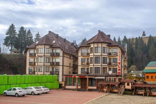a large building with cars parked in a parking lot at Villa Vlad & Spa in Bukovel