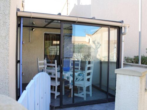une chambre en verre avec une table et des chaises sur un balcon dans l'établissement Pavillon cosy 6 pers, plage Grazel, terrasse, véranda, parking privé - FR-1-229-774, à Gruissan