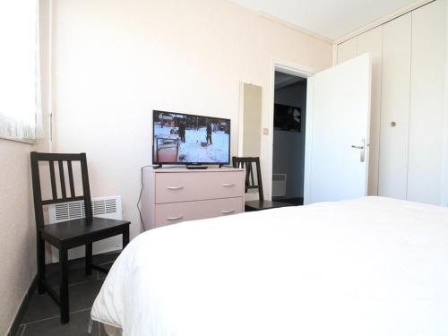 une chambre avec un lit, une télévision et une chaise dans l'établissement Spacieux T2 à Balaruc-les-Bains, cuisine séparée, climatisation, WiFi, proche Thermes - FR-1-553-51, à Balaruc-les-Bains