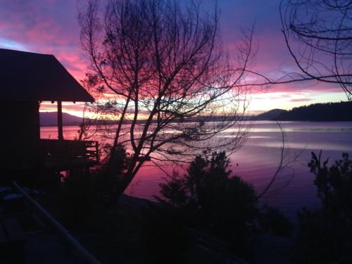 a sunset over a body of water with a house at Cabañas Borgolafquen in Panguipulli