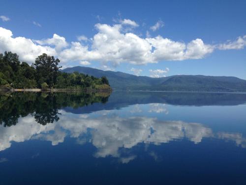 a large body of water with trees and clouds in the sky at Cabañas Borgolafquen in Panguipulli