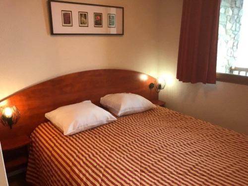 una camera con un letto con due cuscini sopra di Appartement La Mongie, 2 pièces, 4 personnes - FR-1-404-266 a Bagnères-de-Bigorre