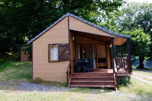 a small cabin with a porch and chairs in it at Chalet in Soursac