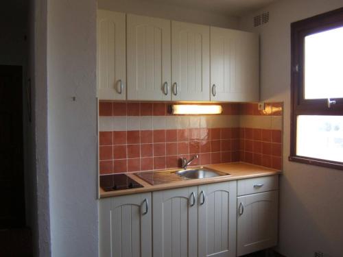 une cuisine avec des armoires blanches et un évier dans l'établissement Appart cosy 4 pers, 1 ch, plage, parking privé - FR-1-81-526, au Barcarès