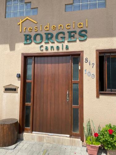 un edificio con una puerta de madera y un cartel en él en RESIDENCIAL BORGES CANELA, en Canela