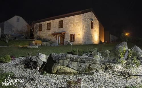 a stone house at night with rocks in front of it at A Cantaruxa Maruxa Turismo Rural in Mondariz