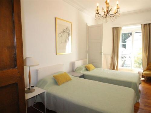 a bedroom with two beds and a chandelier at Grand T2 Ensoleillé à Luchon, Face aux Thermes, pour 4 Pers., Proche Télécabine - FR-1-313-165 in Luchon