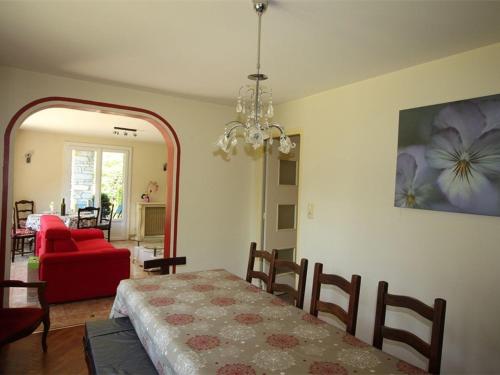 ein Esszimmer mit einem Tisch und einem roten Sofa in der Unterkunft Appartement Bagnères-de-Luchon, 3 pièces, 6 personnes - FR-1-313-177 in Luchon