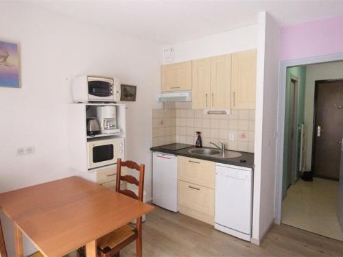 une cuisine avec une table en bois et une cuisine avec une salle à manger dans l'établissement Studio cosy à Luchon - Balcon, garage privé, animaux admis, télécabine à proximité - FR-1-313-183, à Luchon