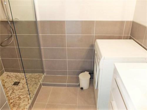 une douche avec une porte vitrée à côté des toilettes dans l'établissement Appartement T2 climatisé, terrasse, plage à 3 couchages - FR-1-251-379, au Lavandou