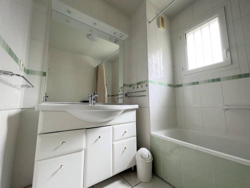 une salle de bain blanche avec un lavabo et une baignoire dans l'établissement Confortable T2 avec terrasse, parking, et internet à Cambo-les-Bains, proche thermes et centre - FR-1-495-95, à Cambo-les-Bains