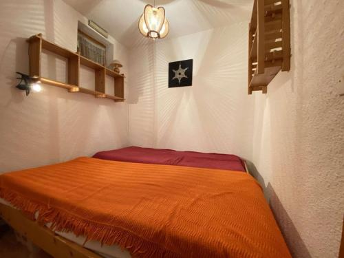 una camera con un letto e una coperta arancione di Appartement Praz-sur-Arly, 1 pièce, 4 personnes - FR-1-603-28 a Praz-sur-Arly