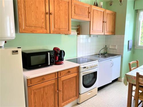 - une petite cuisine avec des placards en bois et un four micro-ondes dans l'établissement Appartement 2 pièces à Quiberon - 56m², proche plage, balcon avec aperçu mer, parking inclus - FR-1-478-195, à Quiberon