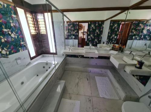 y un baño grande con 3 lavabos, bañera y bañera. en Villa Francesco en Pipa