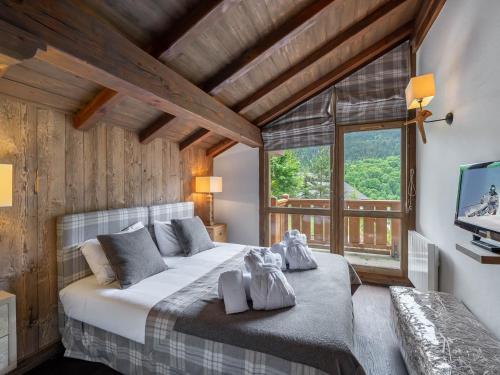 ein Schlafzimmer mit einem großen Bett und einem großen Fenster in der Unterkunft Chalet familial avec jacuzzi et salle de cinéma - FR-1-565-65 in Les Allues