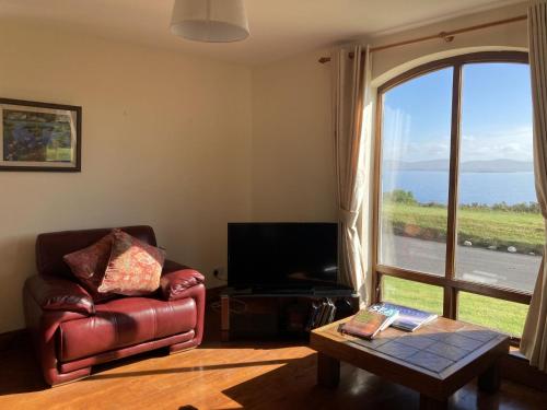 a living room with a leather chair and a large window at No 10 Coastguard Station in Renvyle