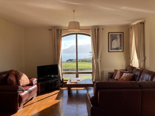a living room with leather furniture and a large window at No 10 Coastguard Station in Renvyle