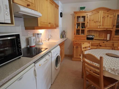 La cuisine est équipée d'une table, d'un évier et d'un four micro-ondes. dans l'établissement Appartement lumineux 2 chambres, parking, terrasse, proche commerces et pistes à Arêches-Beaufort - FR-1-342-226, à Beaufort