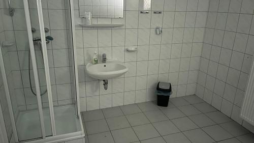 La salle de bains blanche est pourvue d'un lavabo et d'une douche. dans l'établissement Parrag Panzió Mátraszentlászló, à Mátraszentimre