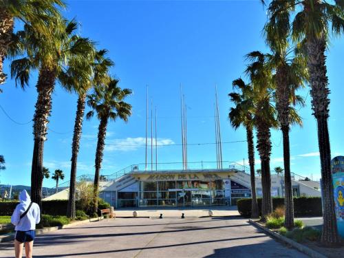 une personne debout devant un bâtiment planté de palmiers dans l'établissement Studio rénové climatisé, 3 couchages, proche port et casino à Cavalaire-sur-Mer - FR-1-226B-98, à Cavalaire-sur-Mer