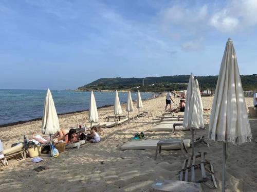 a group of people sitting on a beach with umbrellas at ENERGY Rêves D'Ô in Grimaud