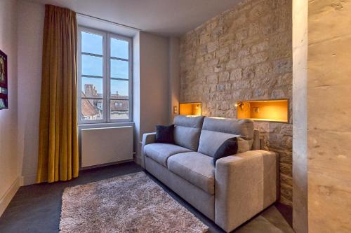 a living room with a couch and a window at Appartement Montagnon - les suites du palais - Classé 4 étoiles, parking privé, vue cathédrale, 3 chambres, PRIMO C0NCIERGERIE in Nevers