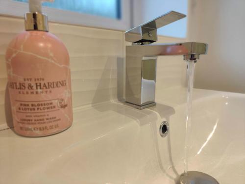 a soap bottle sitting on top of a bathroom sink at Saxon Corner: BRAND NEW 3 bedroom House in Emsworth